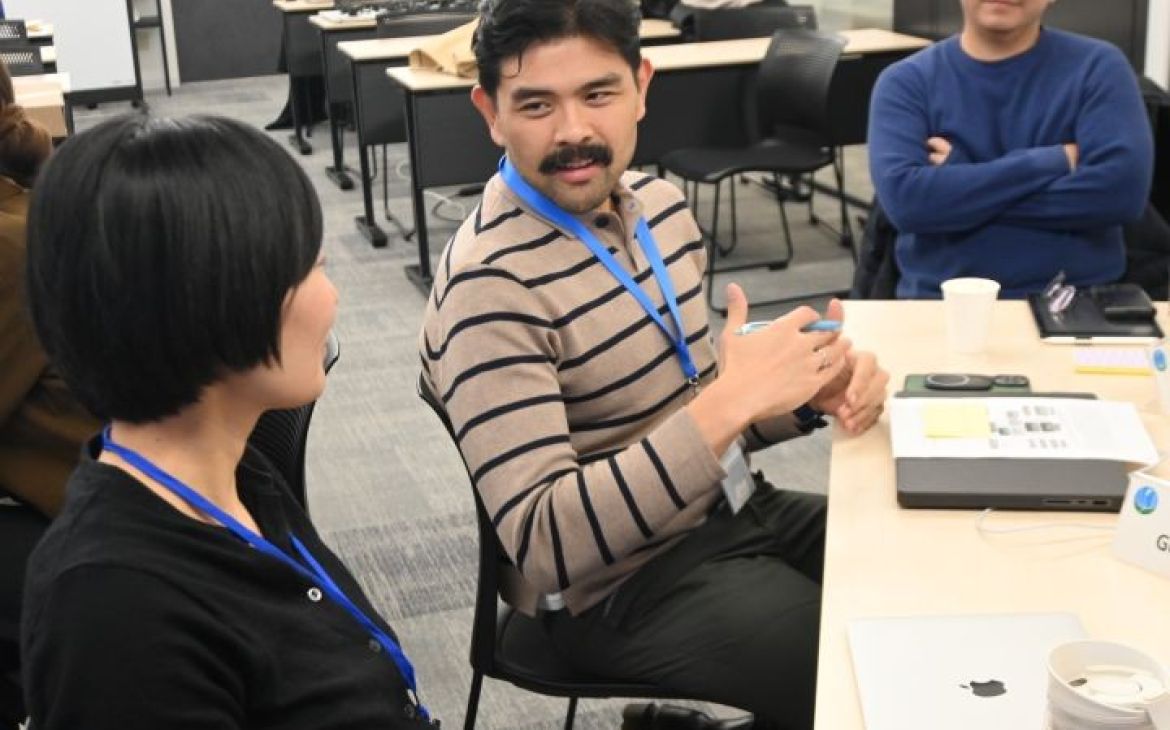 A participant sitting at the table and speaking to another participant to the right