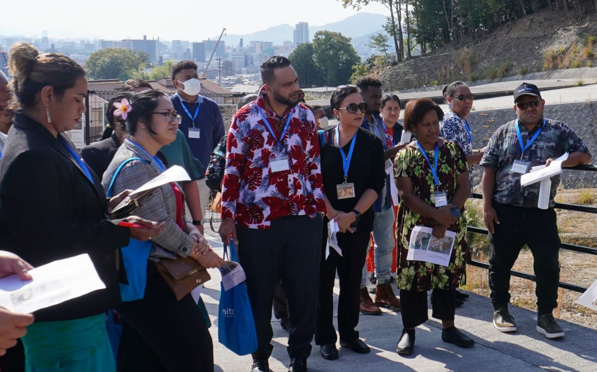 A large group of participants standing outside with documents in their hands, at a study tour