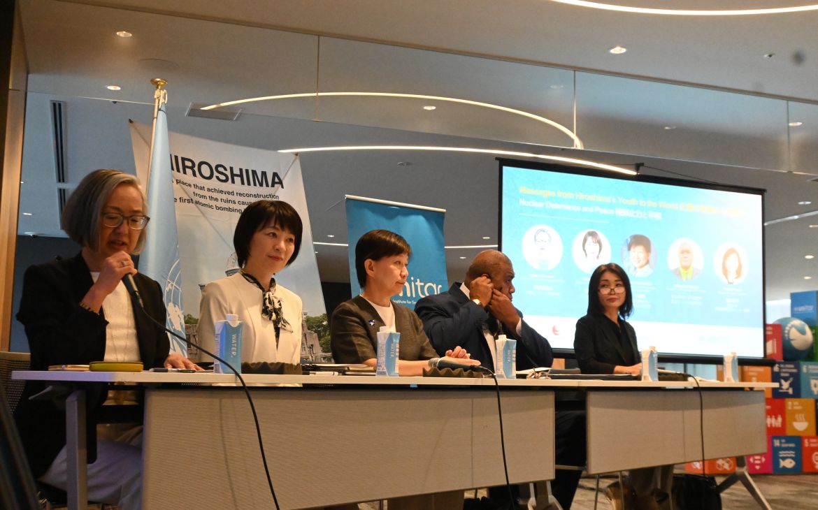 Moderator and five panellists sitting in the front with a screen behind