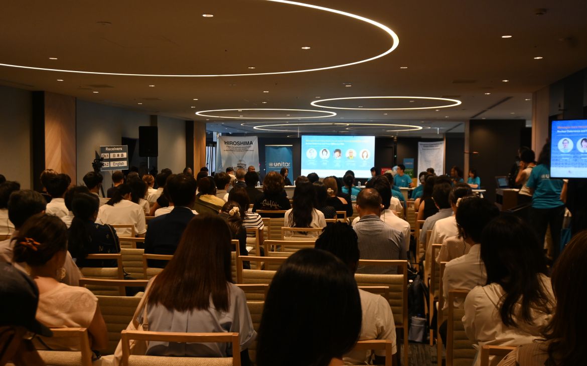 Hiroshima Youth Ambassadors Challenge Nuclear Deterrence and Explore Paths to Abolition on 6 August 2026 session taking place in a dark room full of participants and panellists sitting in the front
