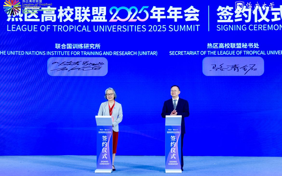 An East Asian woman and man stand at their podiums in the middle of a big blue stage.