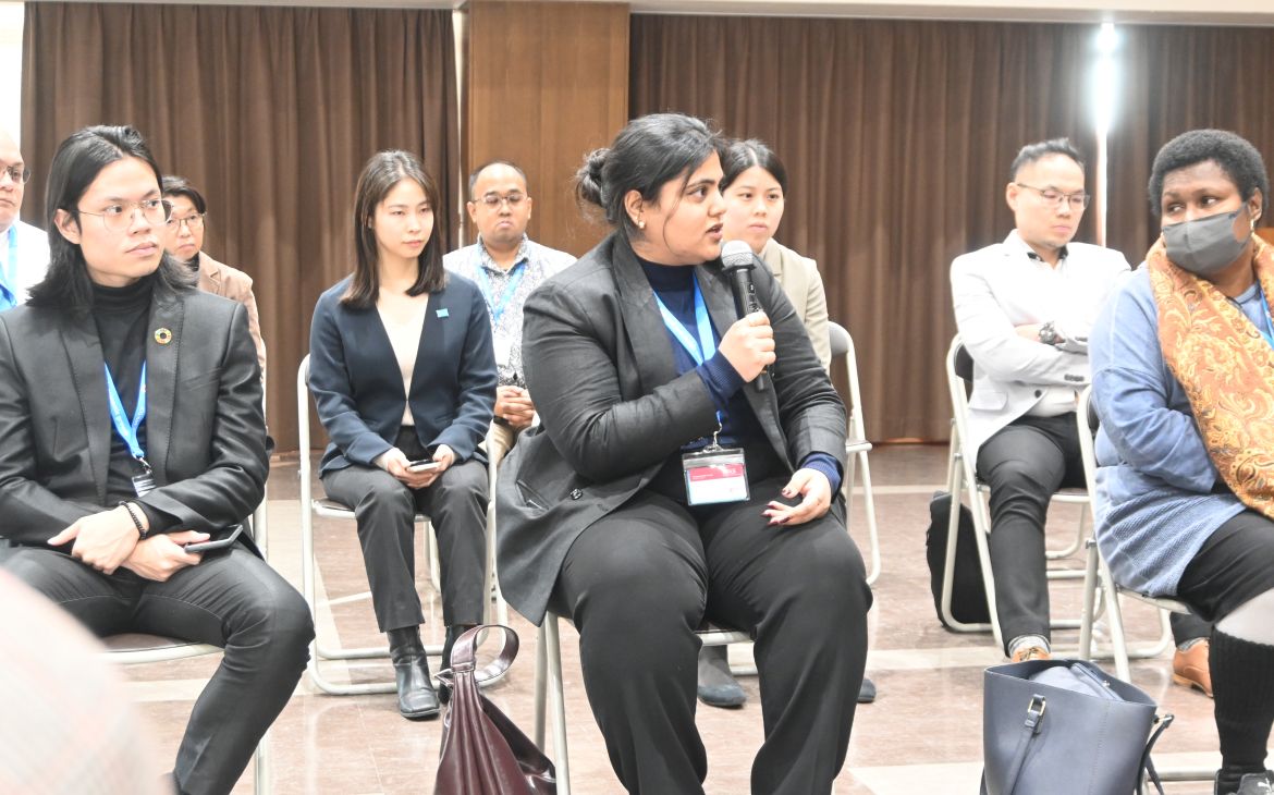 UNITAR training participant sitting in a lecture and speaking with a microphone