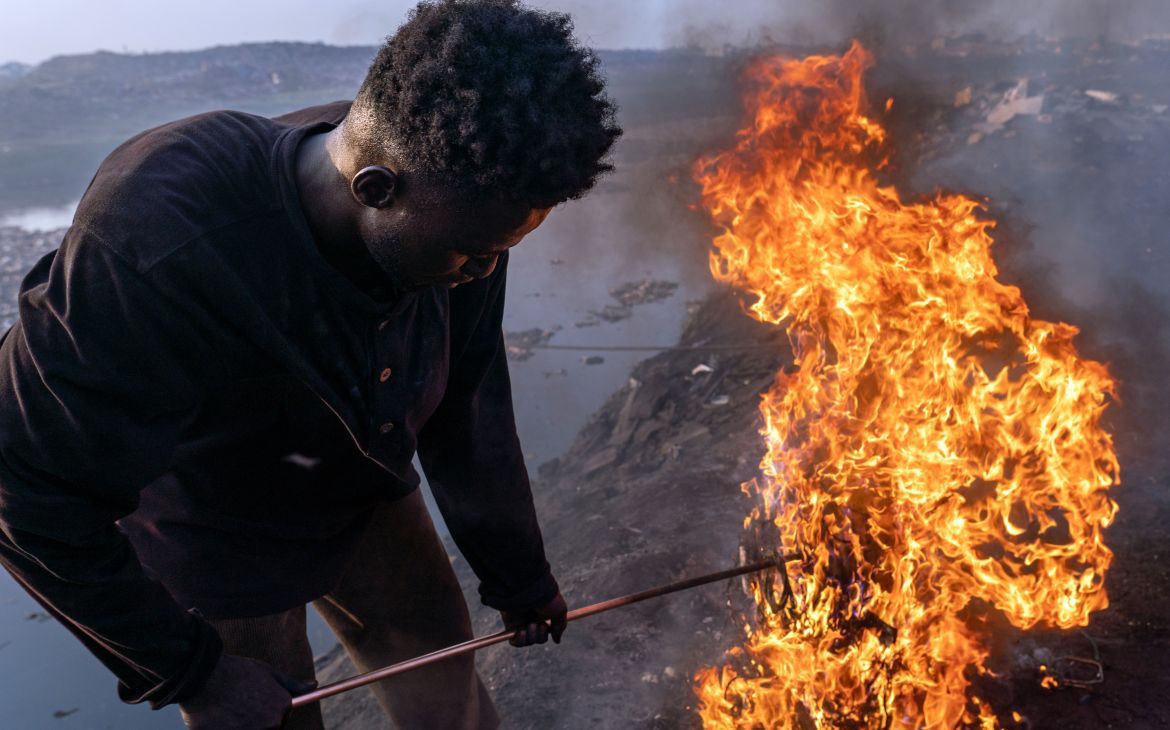 Old Fadama, Accra, Ghana, February 9, 2023. Simon Aniah, 24, burns scrap electrical cables to recover copper by the Korle Lagoon. © Muntaka Chasant for Fondation Carmignac