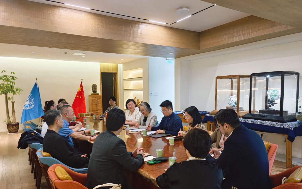 Business professionals seated around a conference table engage in discussion.