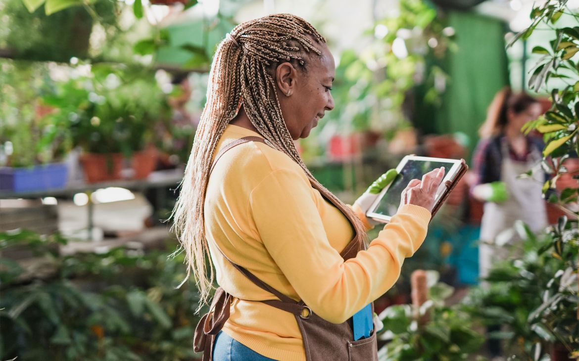 African woman using digital tablet while working in a greenhouse
