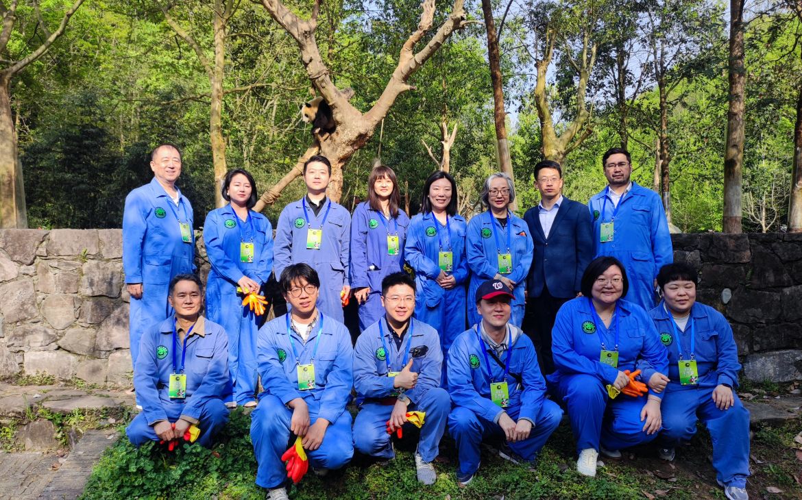 East Asian men and women with uniforms in the group pose.
