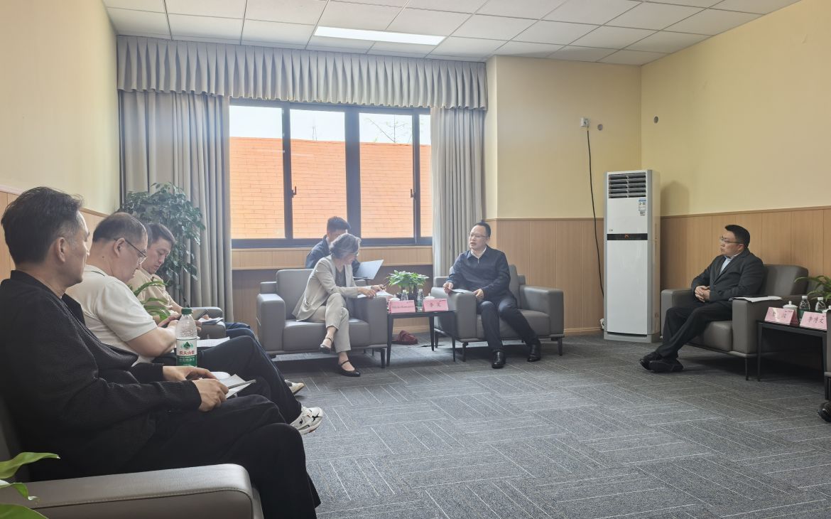 Professionals in business attire sit in sofas around a room and discuss.
