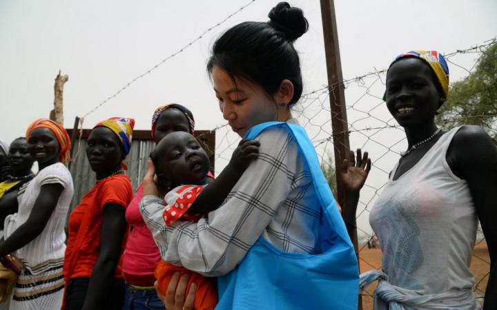 UNHCR’s Eujin Byun holds a refugee baby in her arms at a refugee camp in South Sudan
