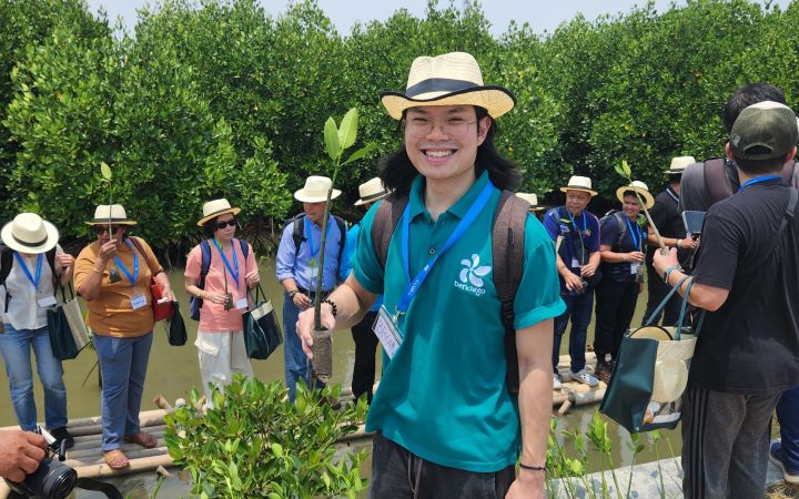 Bryan Sinatra holding a small mangrove sapling, ready to be planted.