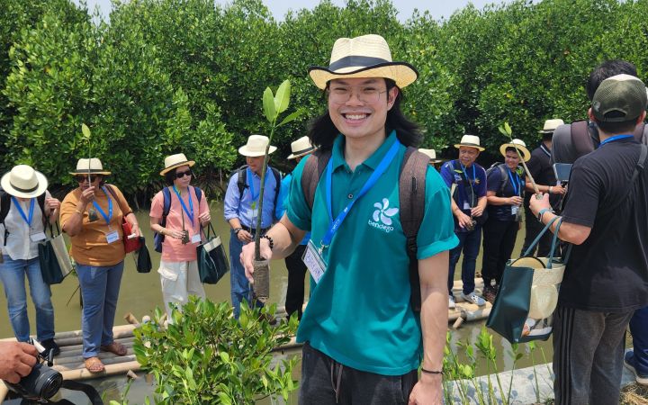Bryan Sinatra holding a small mangrove sapling, ready to be planted.