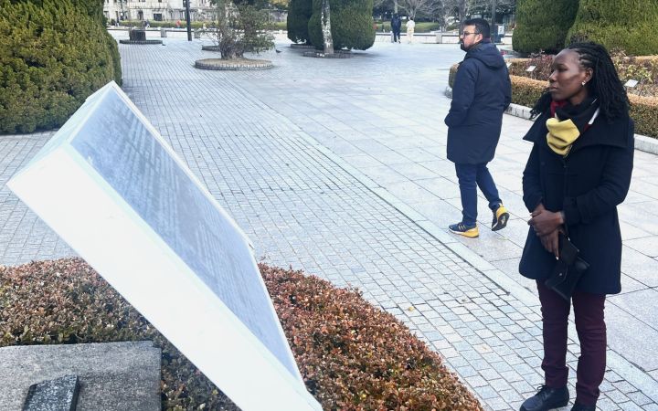 A participant at the Hiroshima Peace Memorial Park, reading an explanation on a stone monument