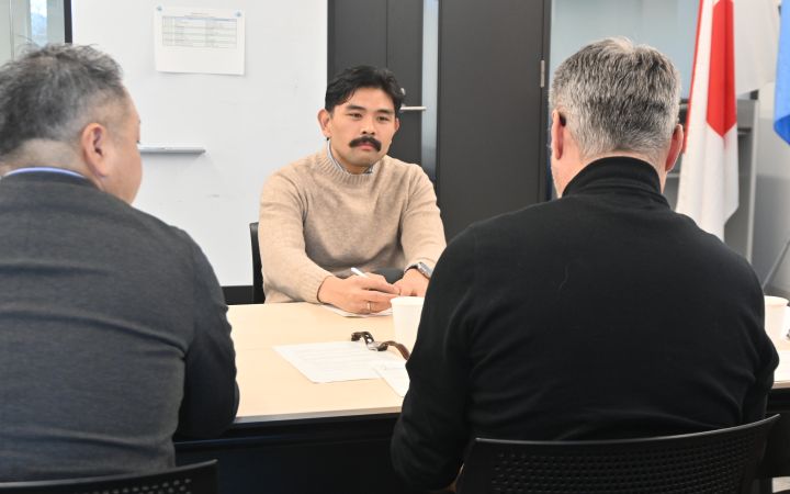 A participant sitting in front of two other participants and in discussion