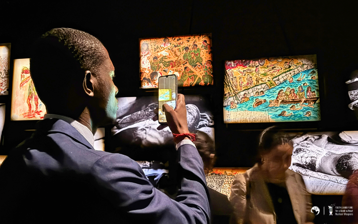A participant taking a photo with their mobile of an image on screen of post atomic bombing in Hiroshima