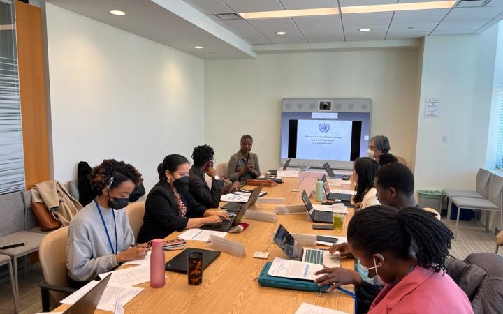 A group of fellows are seen sitting around a conference table, listening to Ms. Sonia Elliott, who is giving a brief overview of disarmament and the First Committee