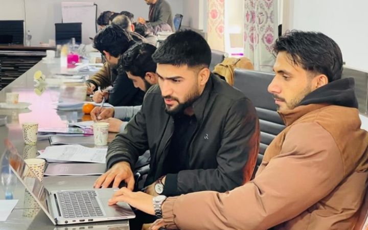 Participants working together in front of a lap-top computer at the UNITAR Entrepreneurship Training Programme