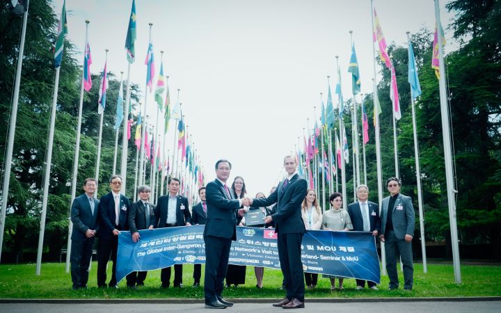 Representatives of the Global Inter-Gangwon Cooperation Network and UNITAR shake hands in front of the Palais des Nations.