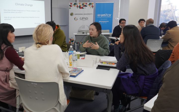A group of five people conducting a group discussion around a white table in a room