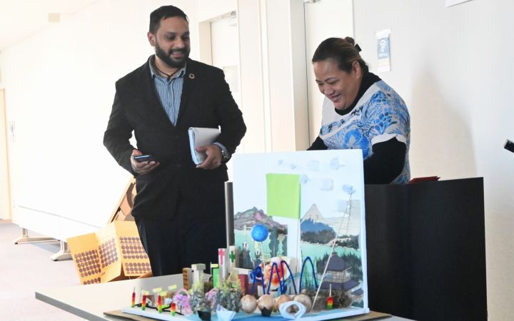 Two programme participants standing in front of a pop-up type material and presenting in a room