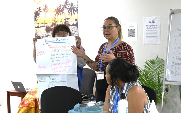 UNITAR Training Participant conducting a presentation using a large paper presentation material being held by another participant