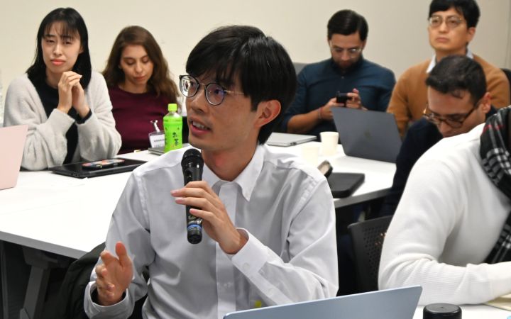 A participant sitting in a group and talking with a microphone in a session
