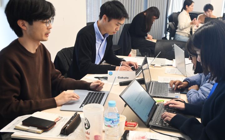 A participant sitting in a group and working on his project with a laptop computer
