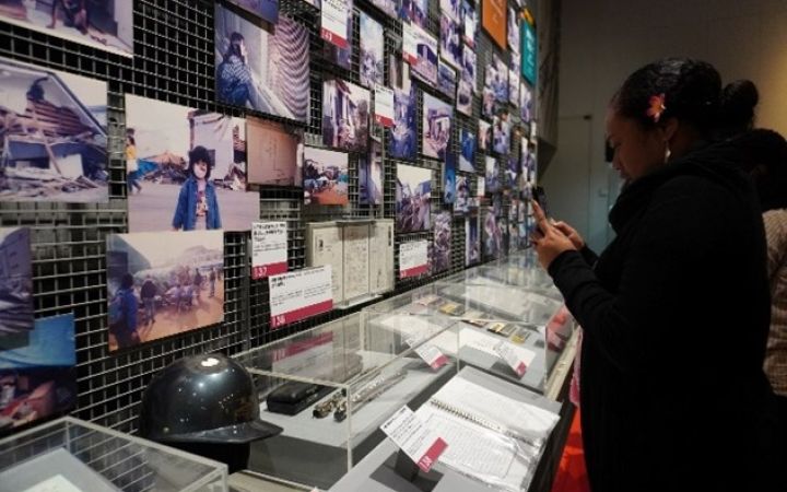 A medium-skinned woman with a flower in her hair studies a display of photos and person items