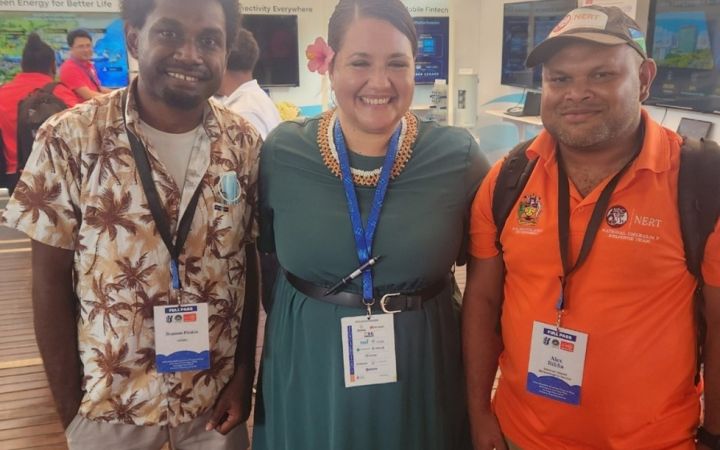 Three UNITAR alumni standing in front of a camera for the Early Warning System Training Programme