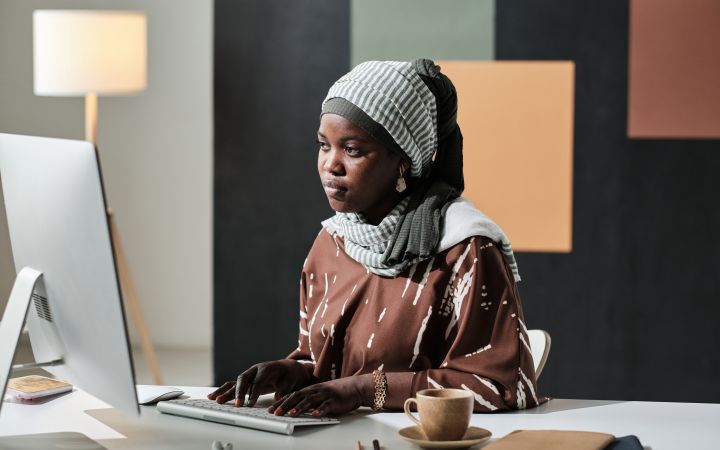 A women sitting in front of a computer and looking at the screen