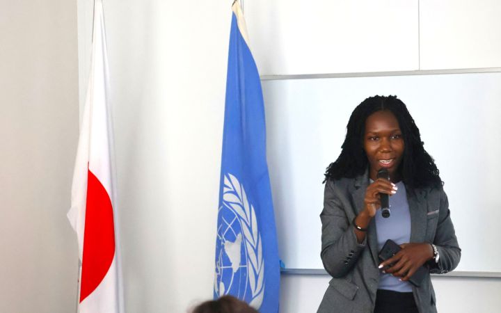 A participant presenting with the UNITAR and Japan flag next to her