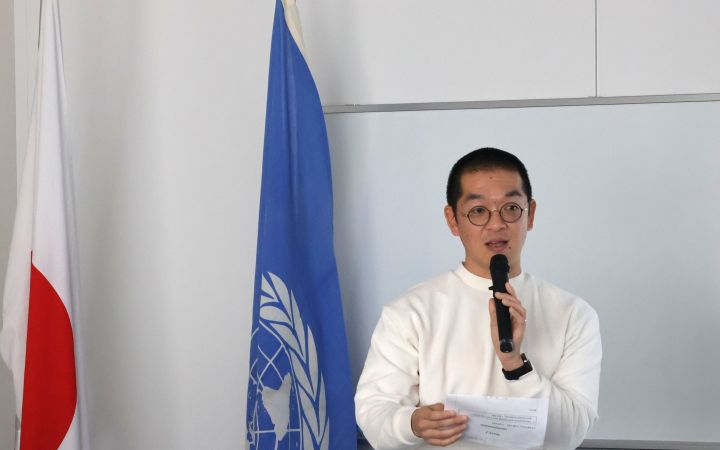 A participant standing in front of podium with a note and a microphone in his hands speaking