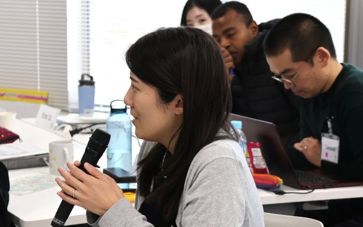 A participant sitting and speaking through a microphone during a training session