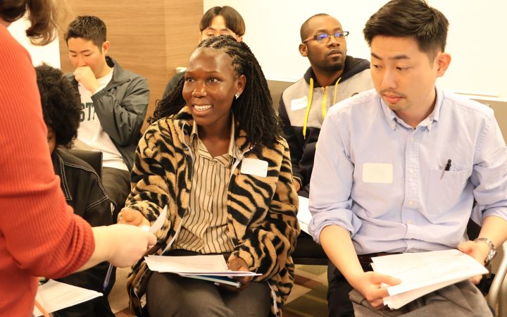 A participant with a smile, receiving a paper document from a staff 