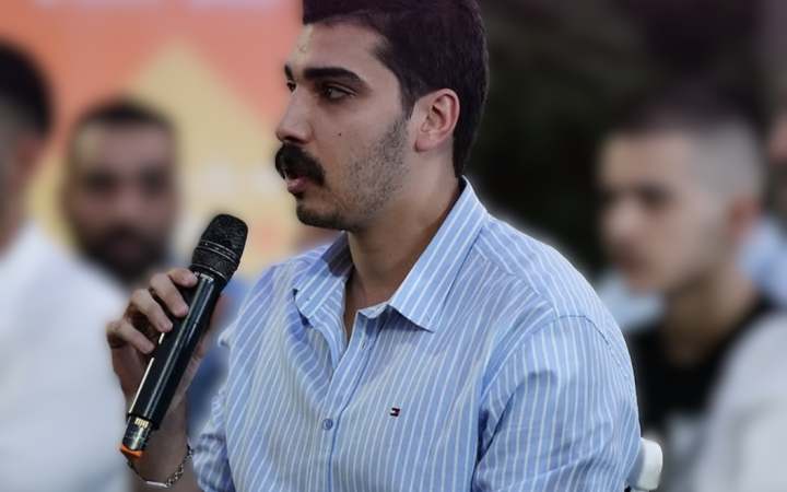 A person sitting in a session and speaking through a microphone