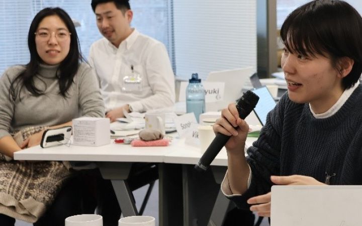 A person sitting in a group speaking on a microphone