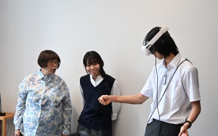 UNITAR Digital Storytelling programme participant using a VR goggle in front of two people in a room
