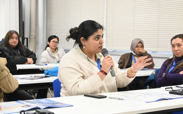A participant sitting and speaking through a microphone during a training session
