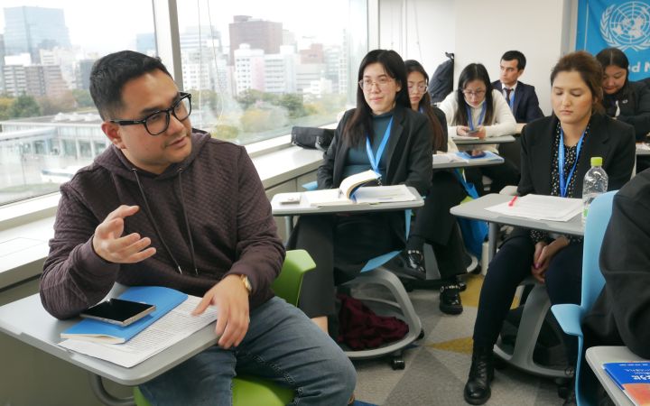 UNITAR training participant speaking during a study session in a conference room with fellow participants