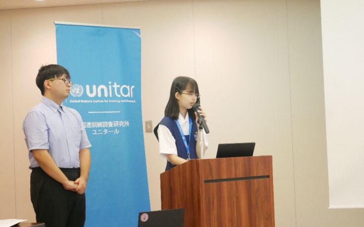 Two high school students presenting with one standing in front of a podium speaking