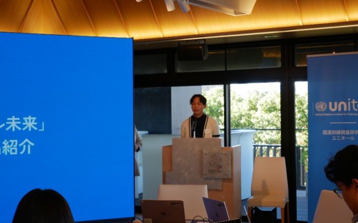 Programme Participant standing in front of a podium with a microphone conducting a presentation in front of other participants
