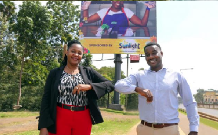 Unilever East Africa’s Home Care Director Henry Muchauraya and Absa’s Director of Business Banking Elizabeth Wasunna touching elbows in front of the Sunlight billboard