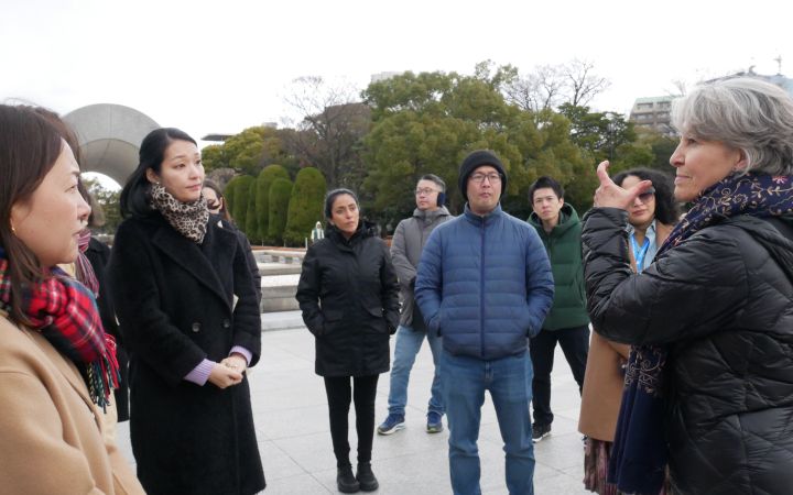 Programme participants at the peace memorial park, standing and listening to an expert speak
