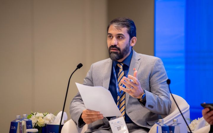 A person speaking to the audience through a microphone with a paper in his hand