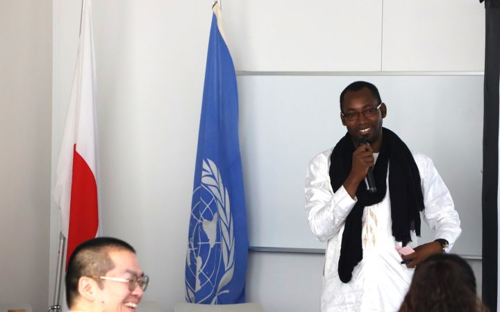  Jacques Dembele conducting a speech next to the UN flag in a meeting room