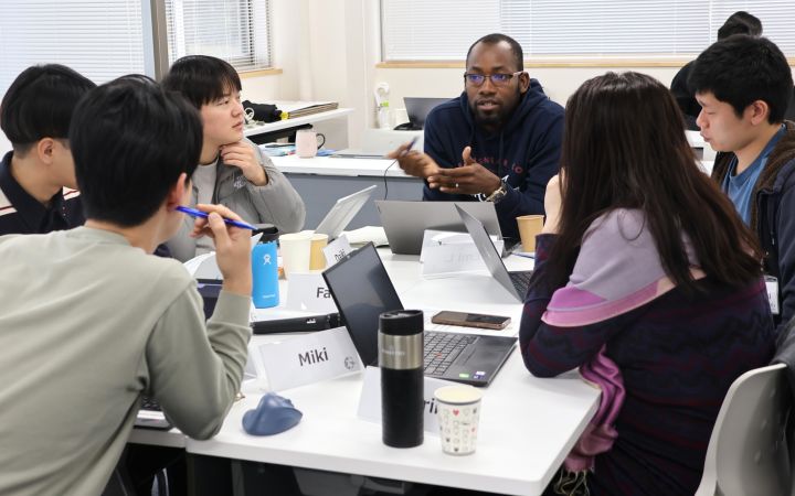 Students sitting at a white square table in discussion at the Primary Course of the Program for Global Human Resource Development for Peacebuilding and Development