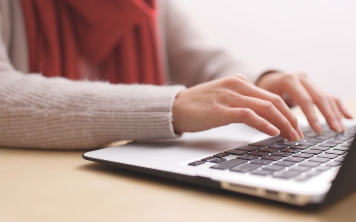 Cropped photo of a woman's hands typing on a laptop